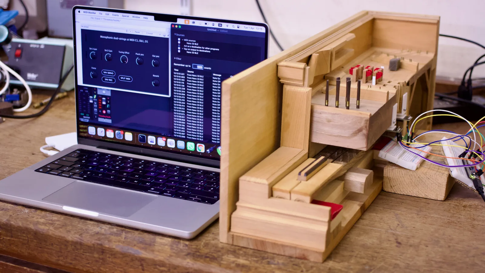 The experimental setup: the three-key mechanical harpsichord prototype connected to a MacBook Pro running the virtual instrument plugin, with the plugin interface and MIDI event log visible on screen.